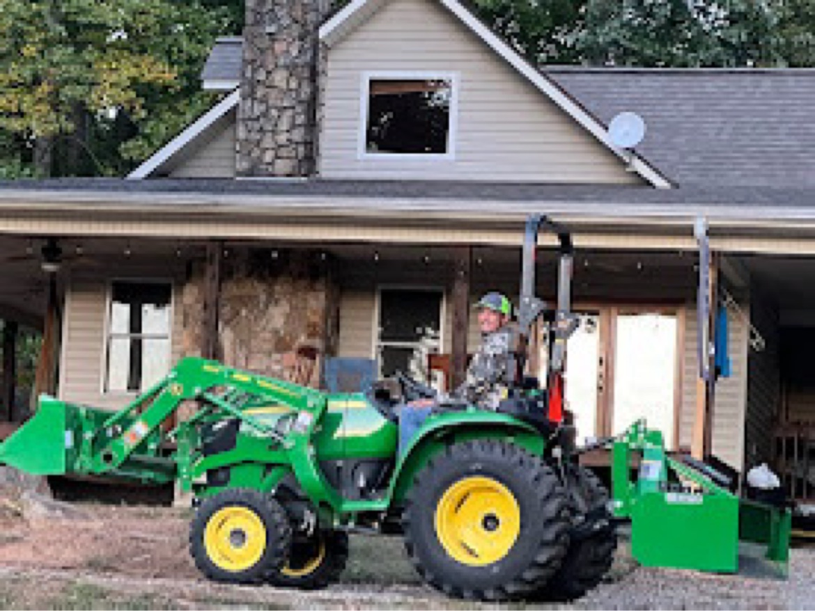 Green compact tractor with front loader and rear attachment